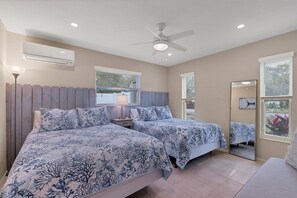 Ein Schlafzimmer mit zwei Betten, einem Deckenventilator und einem großen Fenster.