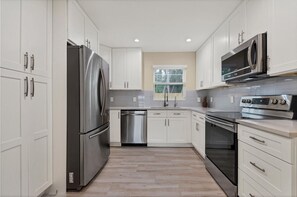 Una cocina moderna con electrodomésticos de acero inoxidable, armarios blancos y suelo con patrón de espiga.