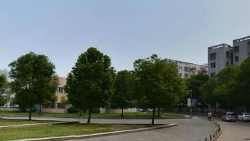 A paved pathway with trees and a building in the background.