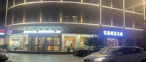 A hotel with a modern facade, illuminated signage, and a visible entrance.