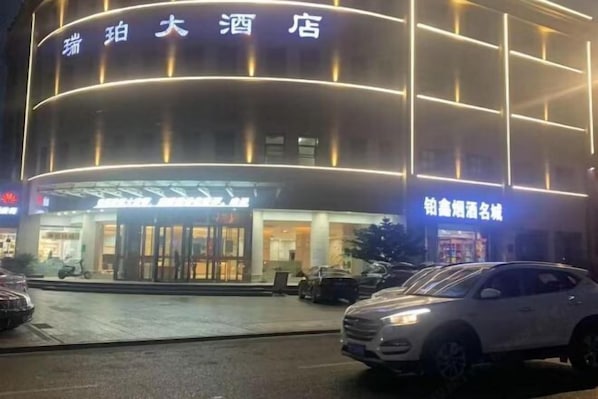 A hotel with a modern facade, illuminated signage, and a visible entrance.