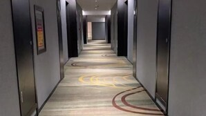 A hallway with a patterned carpet and doors on both sides. - Ruipo Hotel (Xiantao)