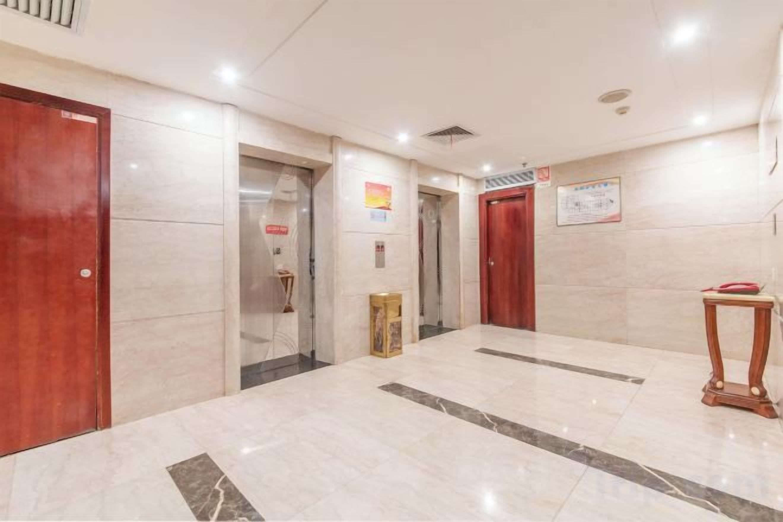 A hotel lobby with marble flooring, wooden doors, and a small table.