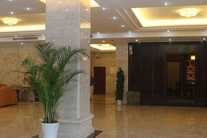Vestíbulo con columnas de mármol, una mesa de recepción y una planta grande en maceta.