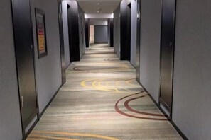 A hotel hallway with carpeted flooring and doors on both sides. - Ruipo Hotel (Xiantao)