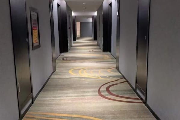 A hotel hallway with carpeted flooring and doors on both sides. - Ruipo Hotel (Xiantao)