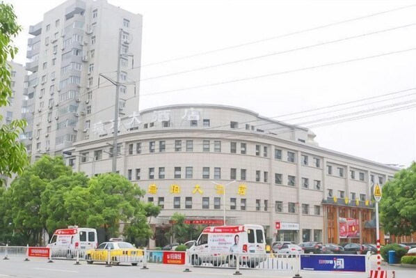 A multi-story building with a curved facade, several windows, and a sign with Chinese characters.