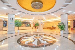 Vestíbulo de hotel con un diseño circular en el suelo, mostrador de recepción y zona de estar.