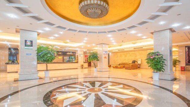 A spacious lobby with a central circular marble design, multiple seating areas, and potted plants. - Ruipo Hotel (Xiantao)