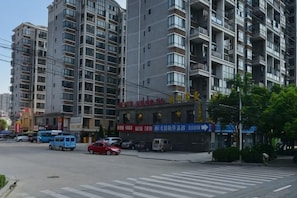 A multi-story residential building with balconies, a crosswalk, and a small storefront with signage. - Ruipo Hotel (Xiantao)