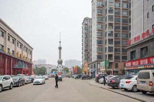 A street with parked cars, a person walking, and buildings with signage.