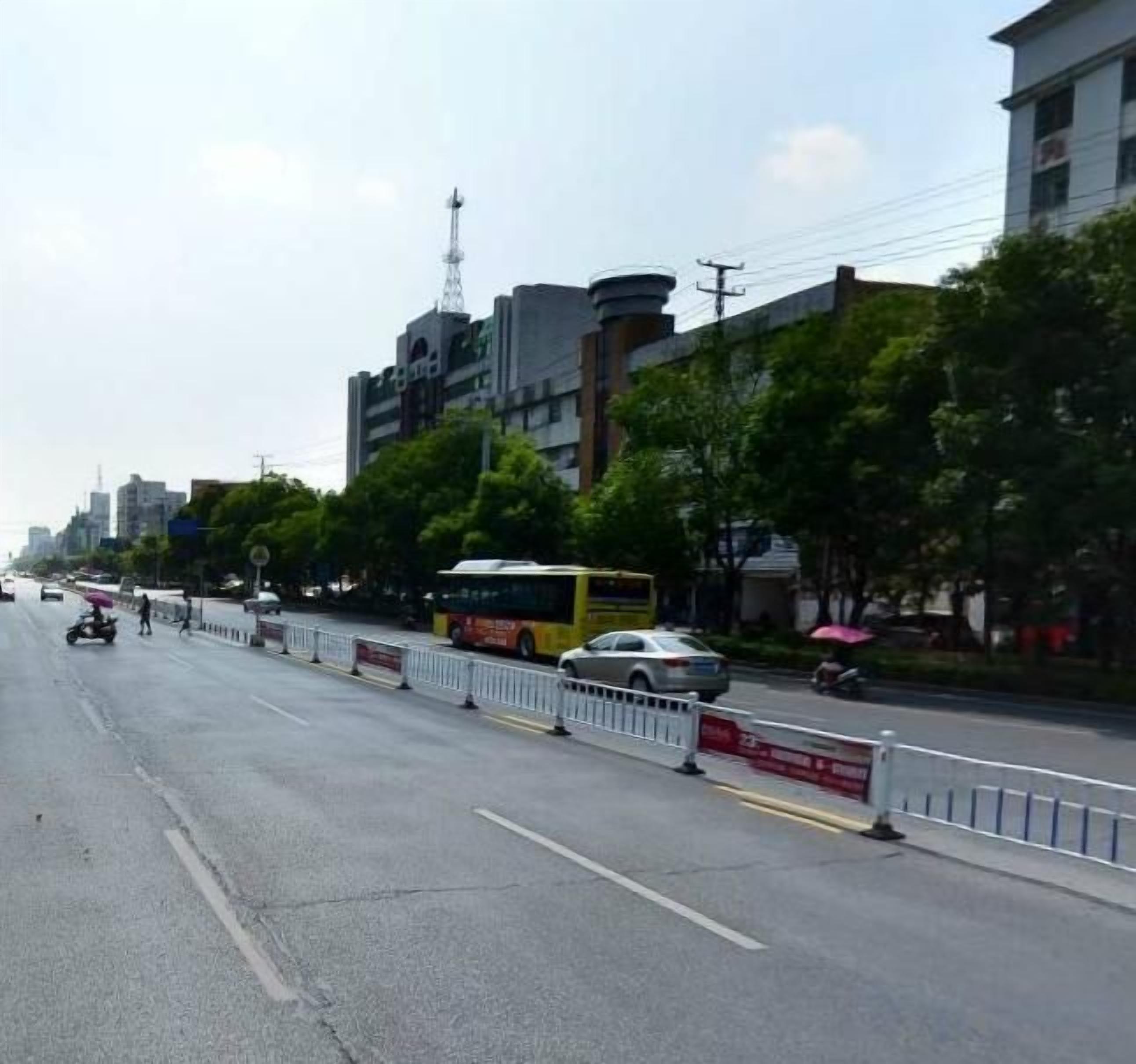A street with a bus, cars, and a pedestrian walkway.