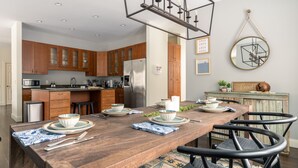 A modern kitchen with wooden cabinets, stainless steel appliances, and a dining area with a wooden table and chairs.