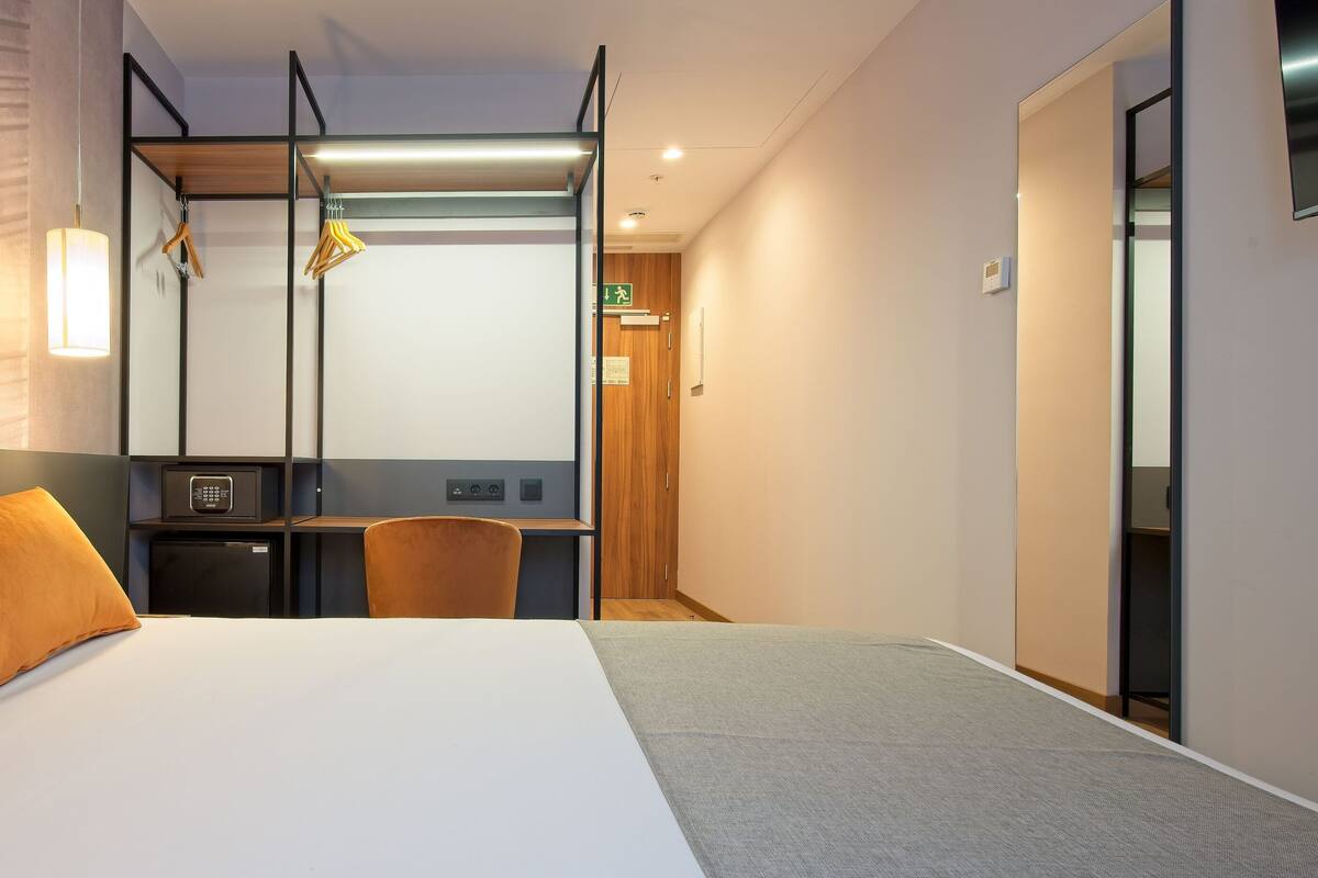 A modern hotel room with a large bed, a desk, and a chair.