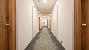 Een hotelgang met houten deuren, een vloerbedekking en een bordje dat een toilet aangeeft.