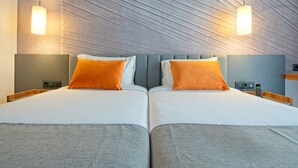 Een tweepersoonsbed met twee kussens, een nachtkastje, een telefoon en een structuurwand.
