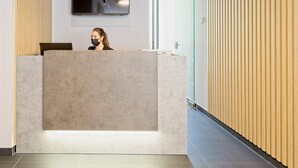 Een receptiezone met een modern ontwerp, met een groot flatscreen-televisiobehangend aan de muur, een receptiebalie en een houten paneelwand.