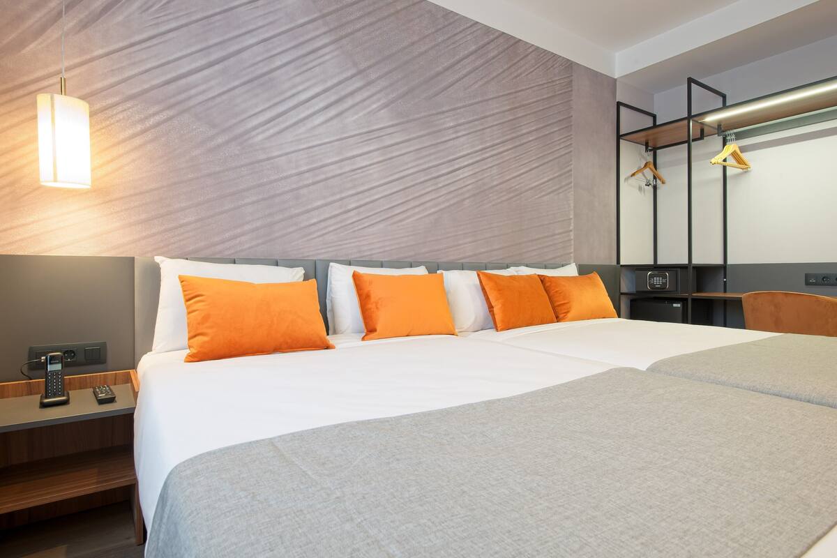 A hotel room with a large bed, a bedside table with a phone, and a wall-mounted TV.