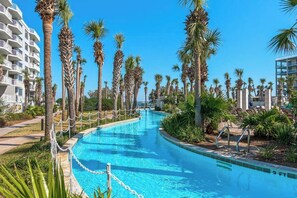 Ein Swimmingpool, umgeben von Palmen und Hotelgebäuden.