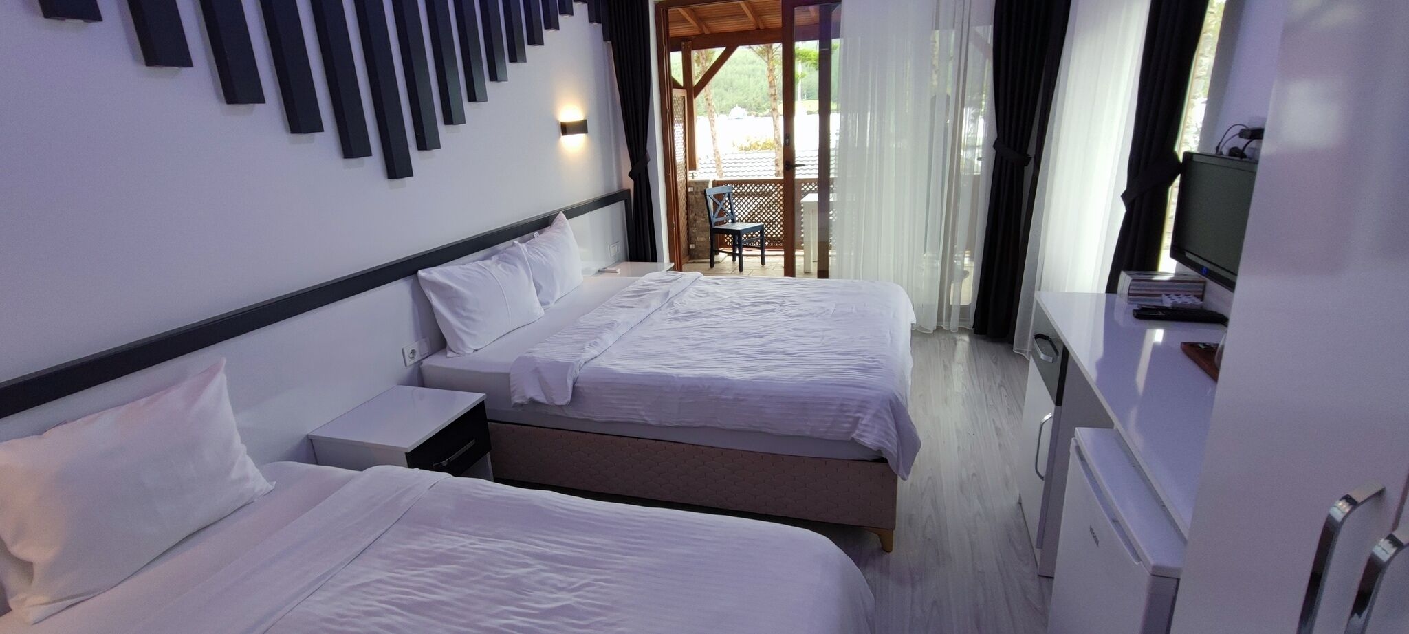 A hotel room with two beds, a TV, and a desk.