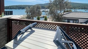 Un balcon avec vue sur un lac, des arbres et des bateaux.