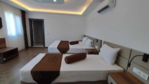 Une chambre d’hôtel avec deux lits, un banc en bois, un téléviseur à écran plat et un plafond doté d’un éclairage encastré.