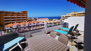 A terrace with a table and chairs, overlooking a coastal area with buildings and the sea. - Comfortable, quiet apartment close to everything (Costa Adeje)