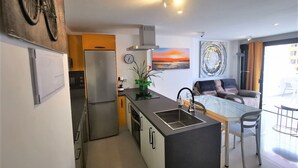 A modern kitchen with a refrigerator, stove, and sink. There is a dining area with a table and chairs. - Comfortable, quiet apartment close to everything (Costa Adeje)