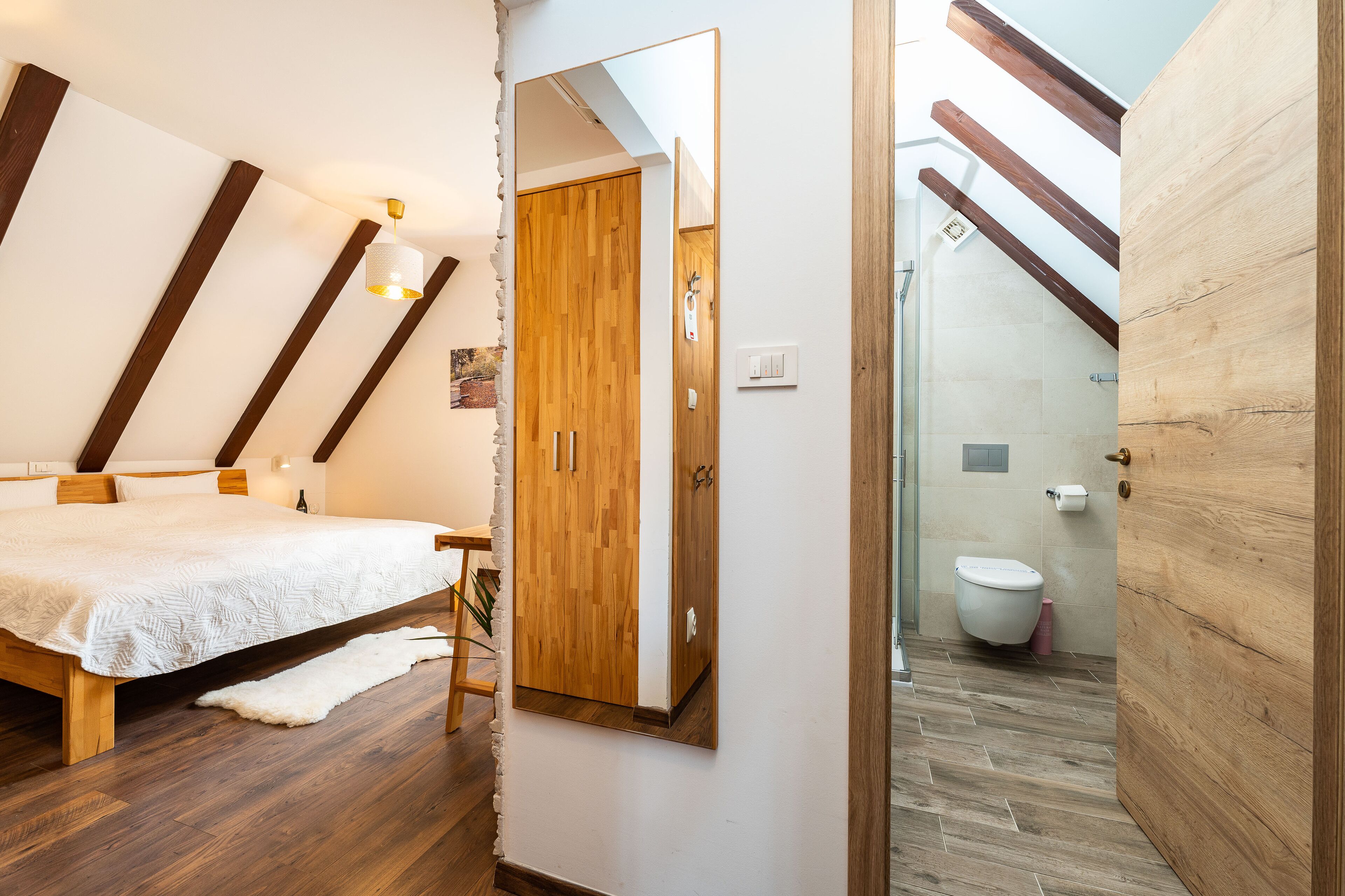 Une chambre avec un lit en bois, un grand miroir et un plafond en bois.