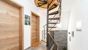 Un interior moderno con una escalera en espiral, puertas de madera y una pared de piedra.
