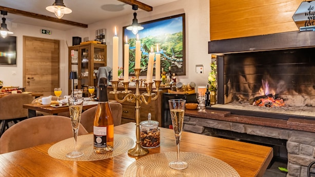Un comedor con una mesa de madera dispuesta para dos personas, con dos copas de champán, una botella de vino y un candelabro.