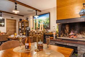 A dining area with a wooden table set for two, featuring two glasses of champagne, a bottle of wine, and a candle holder. - B&B Villa Sumrak Plitvica Rooms (Plitvicka Jezera)
