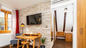 Una sala de estar moderna con pared de piedra, muebles de madera, televisor de pantalla plana y un ventanal con cortinas.