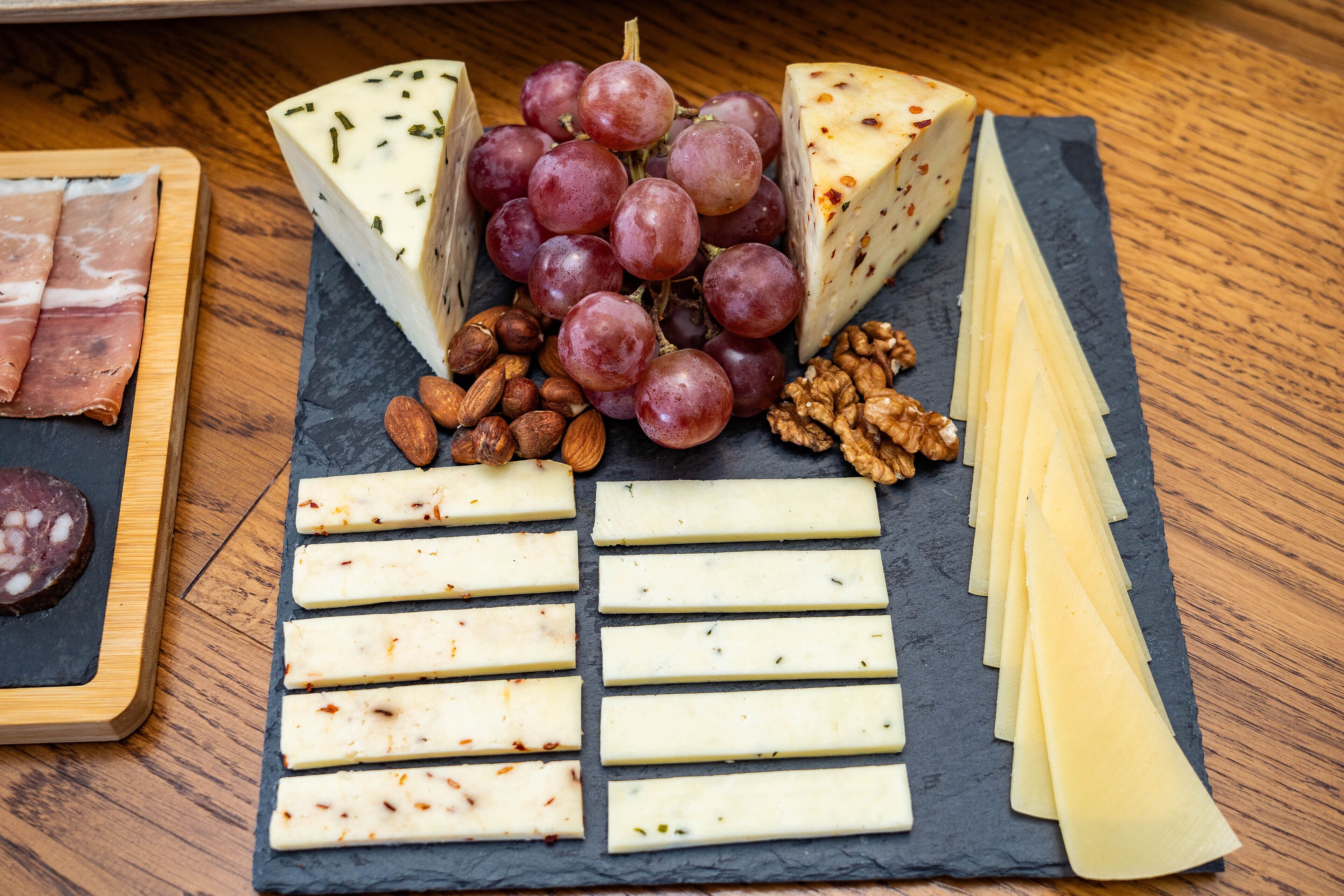 A charcuterie board with various cheeses, grapes, nuts, and cured meats.