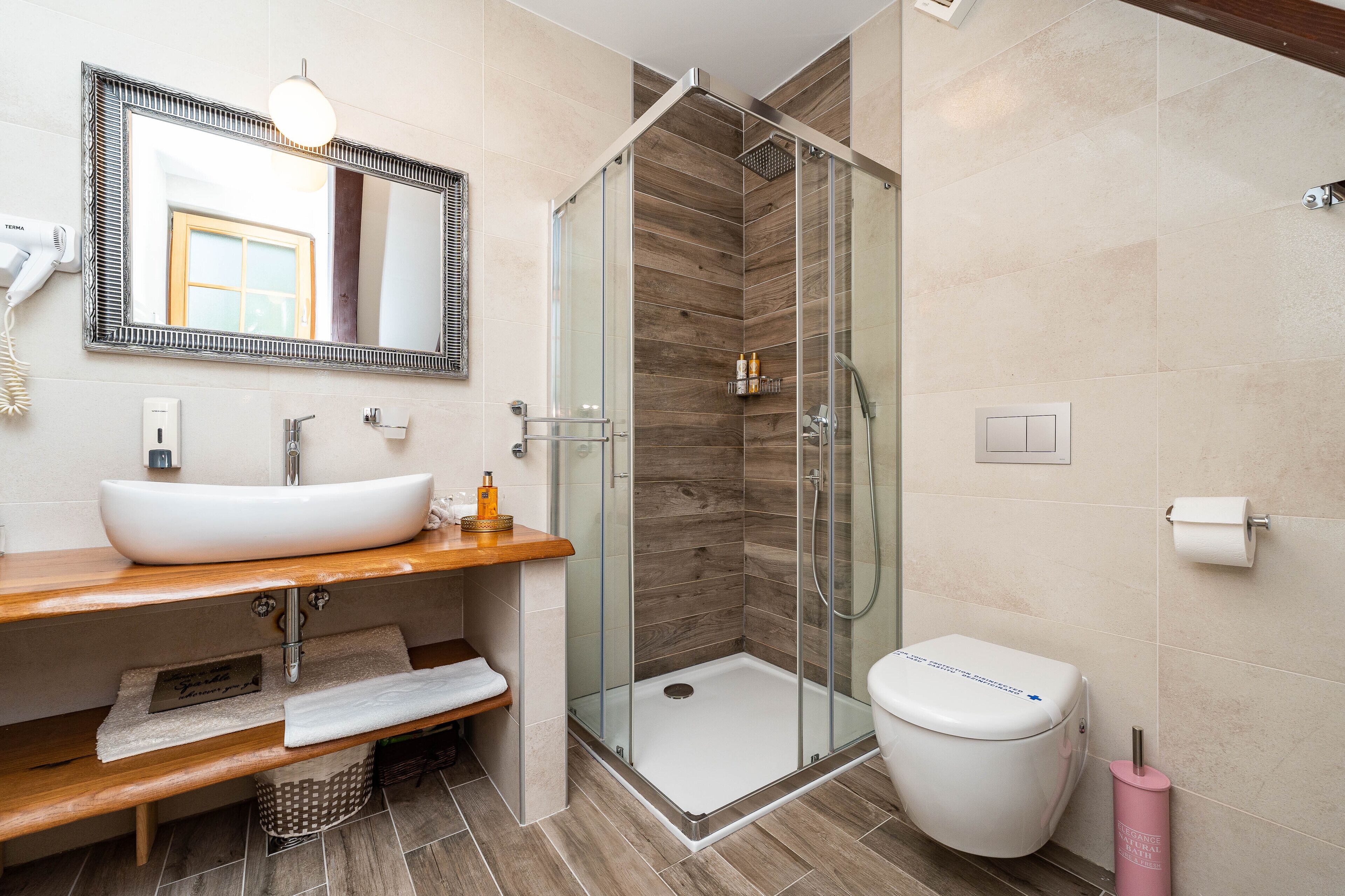 A modern bathroom with a glass-enclosed shower, a white sink, and a toilet.