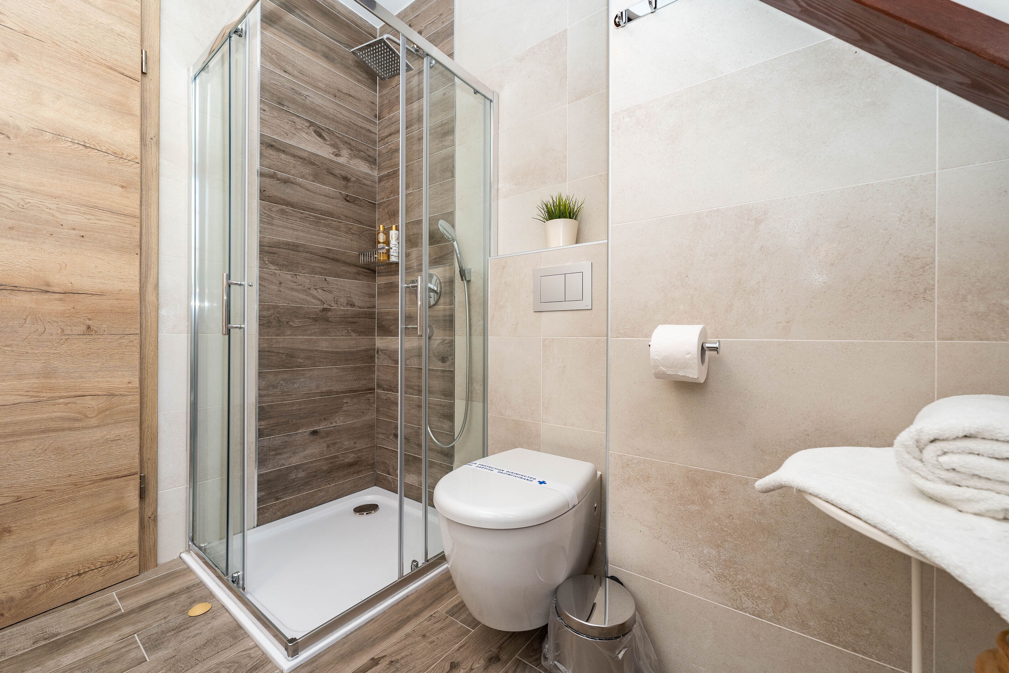 Une salle de bain moderne avec une douche à parois de verre, des toilettes et un porte-serviettes.