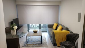 Ein modernes Wohnzimmer mit einer Couch, einem Couchtisch und einem Fernseher auf einem Lowboard.