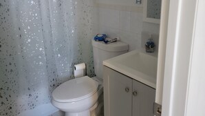 Ein Badezimmer mit Toilette, Duschvorhang, Waschbecken und Spiegel.