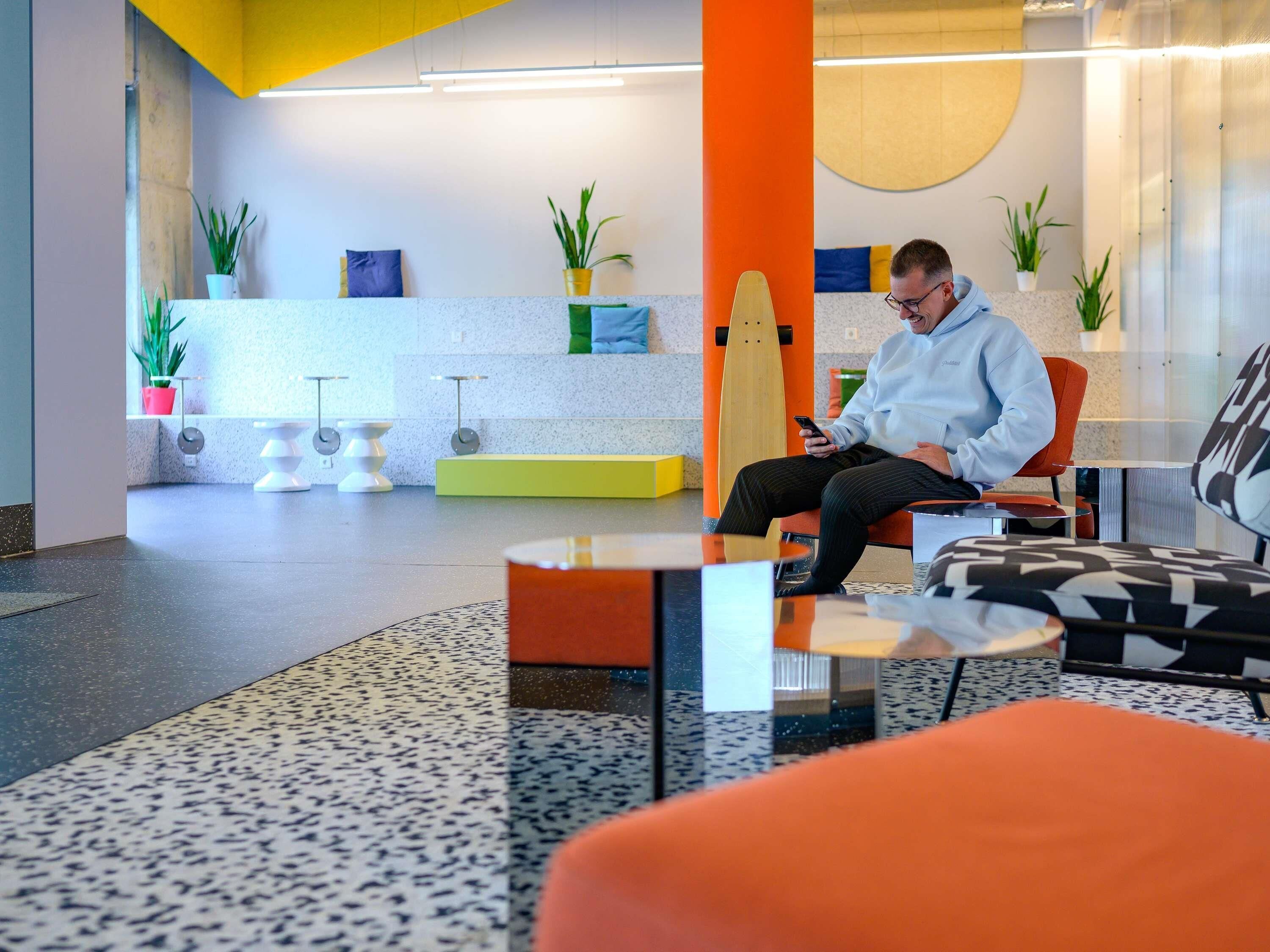 A modern interior with a person seated on a chair using a smartphone.