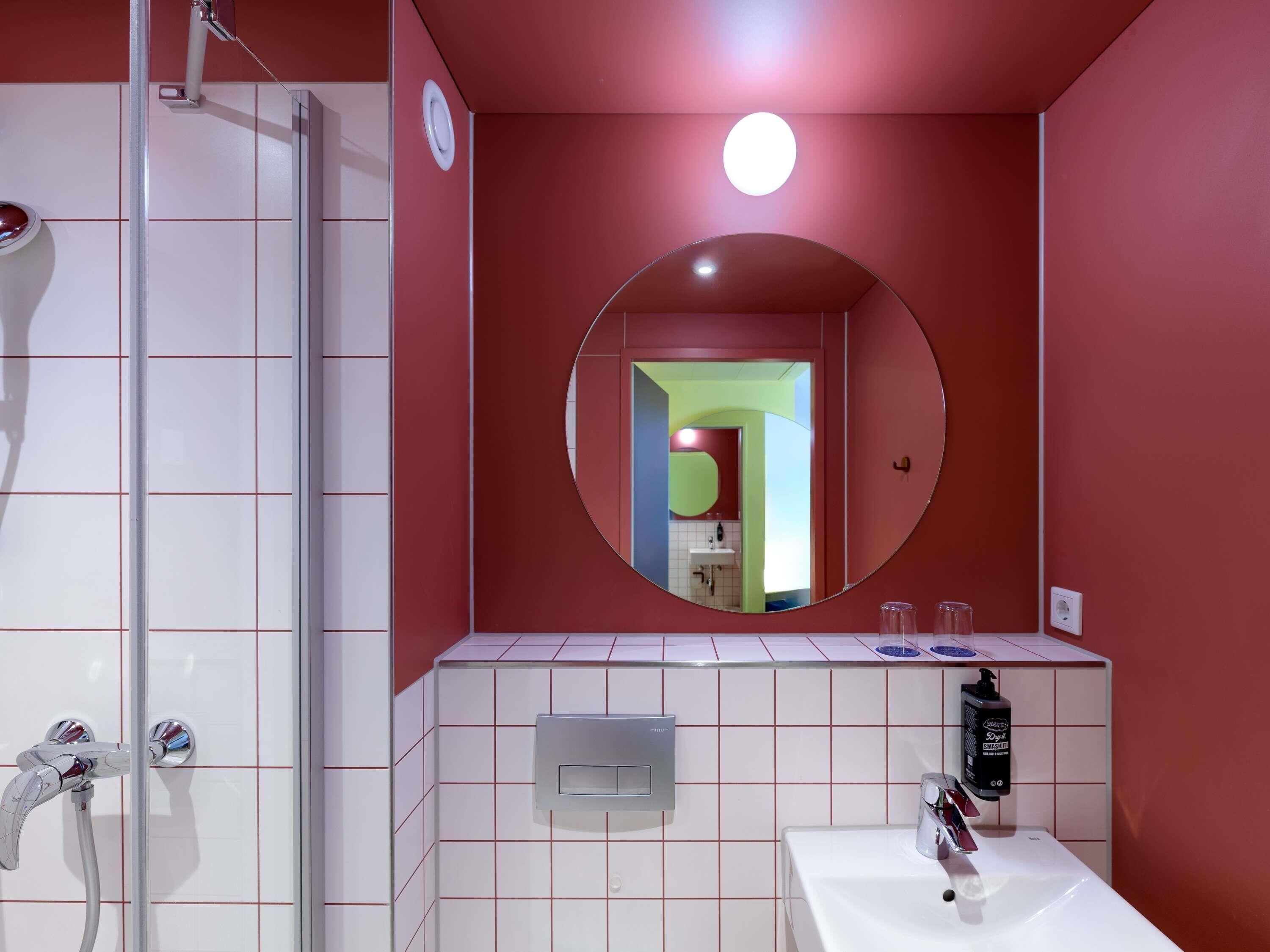 Une salle de bain équipée d’une douche, d’un lavabo, d’un miroir et de toilettes.