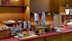 Een ontbijtbuffet met diverse etenswaren, een koffieapparaat en een fruitsapautomaat.