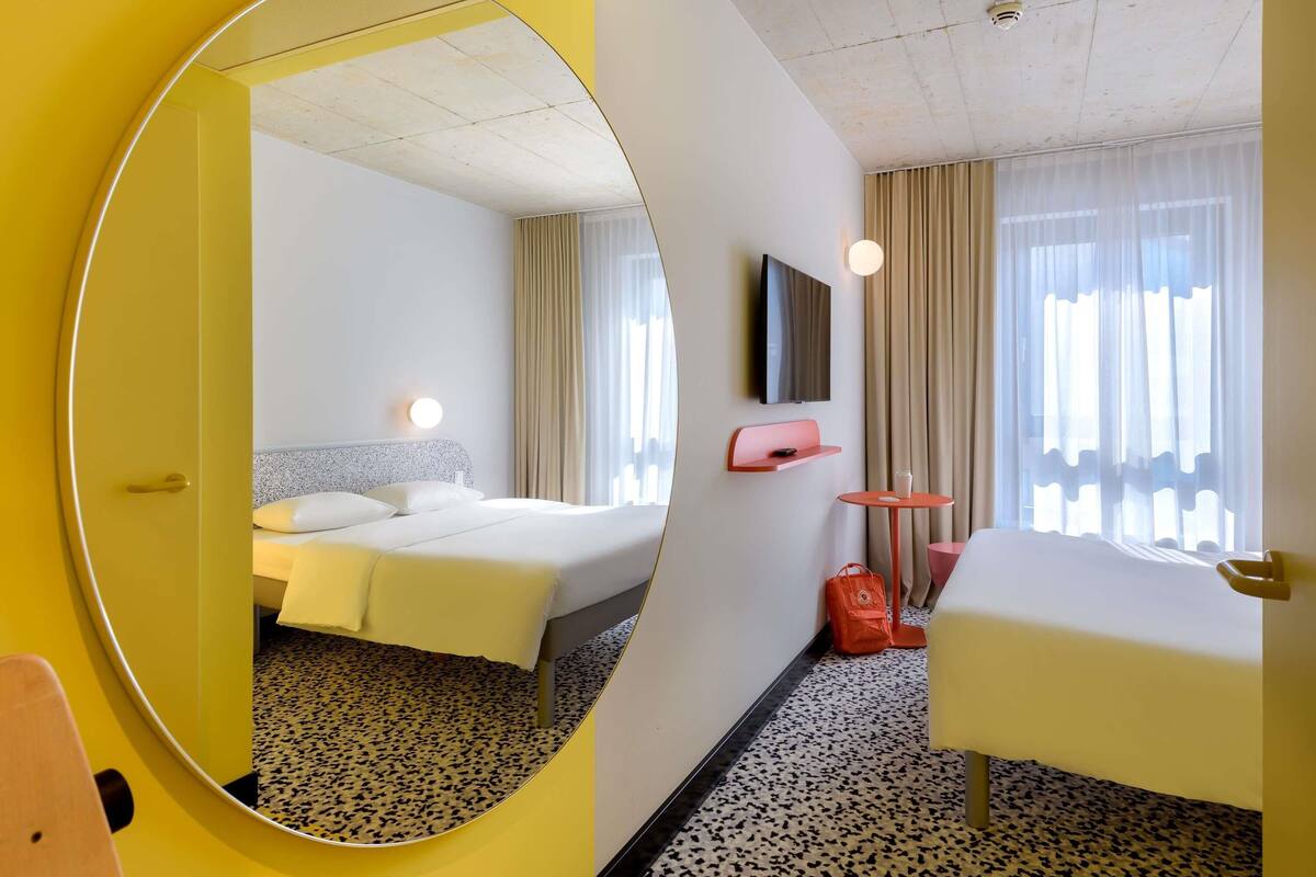 Een hotelkamer met een bed, bureau, stoel, televisie en spiegel.