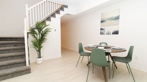 Een modern interieur met een trap, een eethoek met een tafel en stoelen, en een kamerplant.