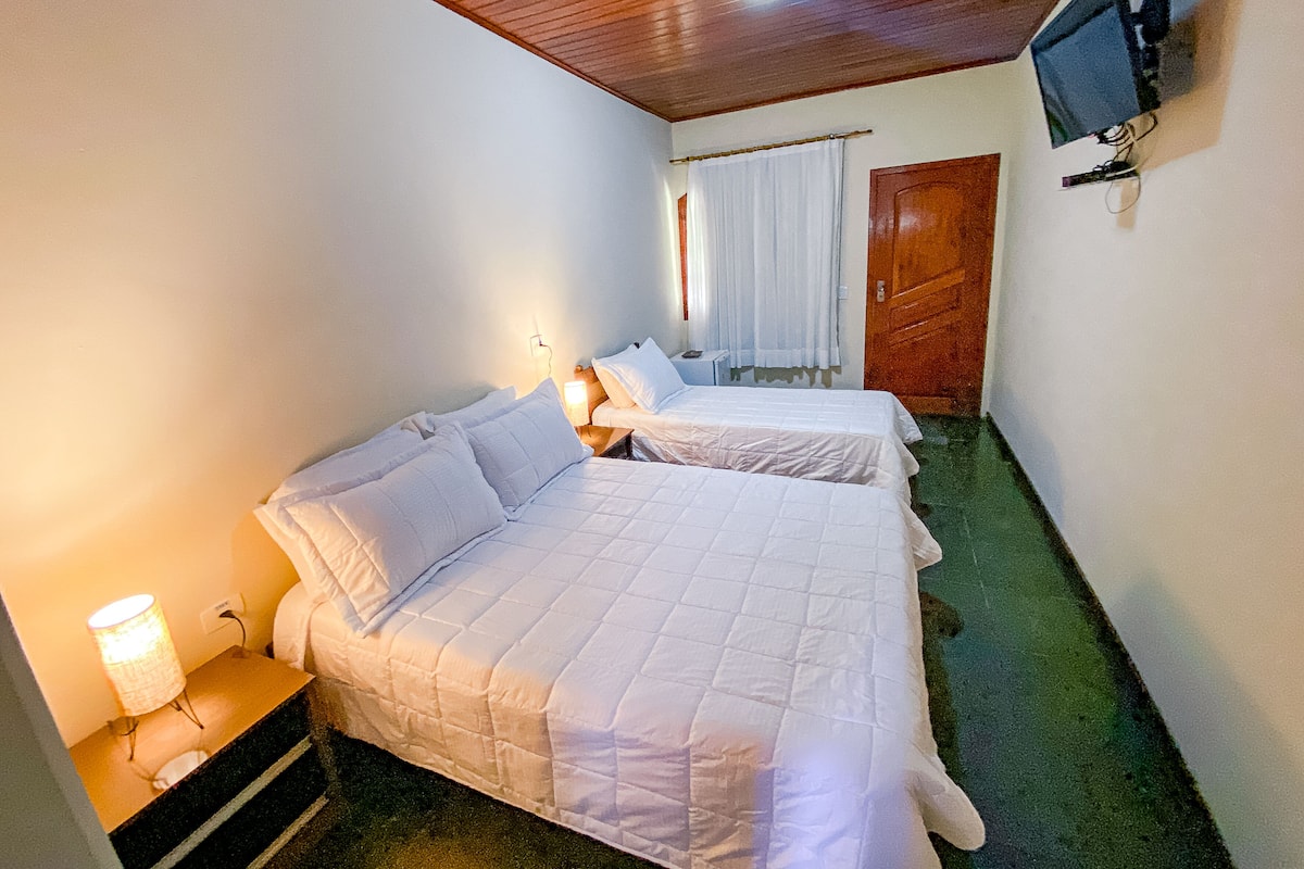 Una habitación con dos camas, un televisor montado en la pared y techo de madera.
