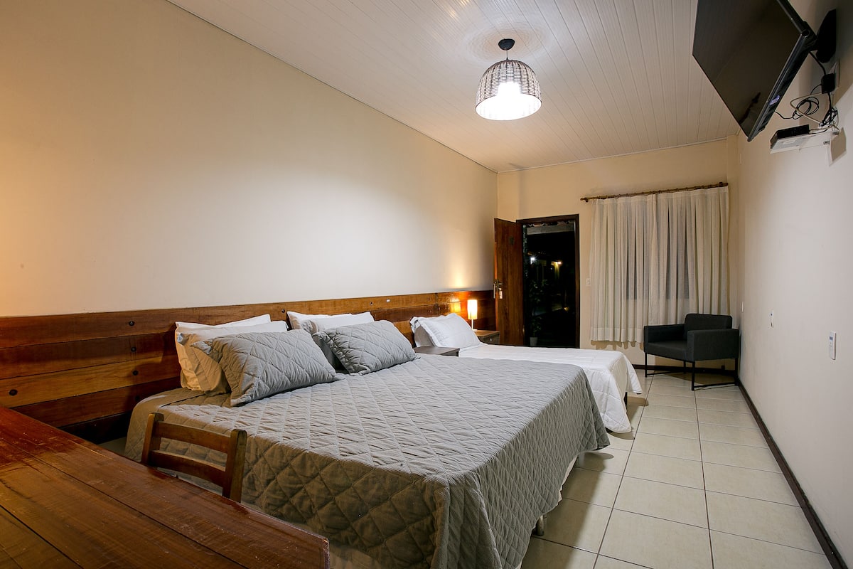 Un dormitorio con una cama grande, un banco de madera, un escritorio y una silla.