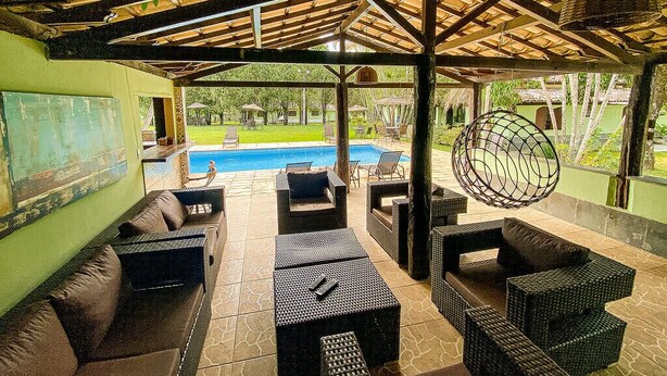 An outdoor patio area with wicker furniture, a pool, and a view of the surrounding landscape. - QUATRO ESTAÇOES PESQ. E HOTEL FAZENDA (Esmeraldas)