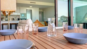 Un comedor con una mesa de madera, cristalería transparente y una cocina moderna al fondo.
