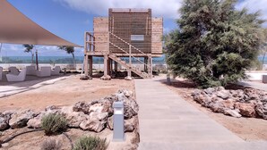 Un área de estar exterior moderna con una estructura de madera y un camino que la conecta.
