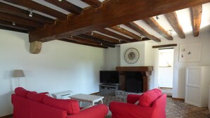 A living room with red sofas, a television, a fireplace, and a clock on the wall.