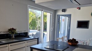 Una cocina moderna con horno empotrado, un comedor con mesa y sillas, y un ventanal que ofrece vistas al exterior.